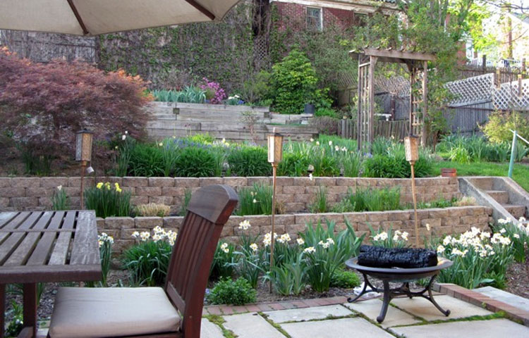 It wasn't long until I grew tired of mowing the steep hill and decided to terrace it. It ended up as a three year project to dig out the hillside (by hand), install a French drain, and build a block wall and patio.